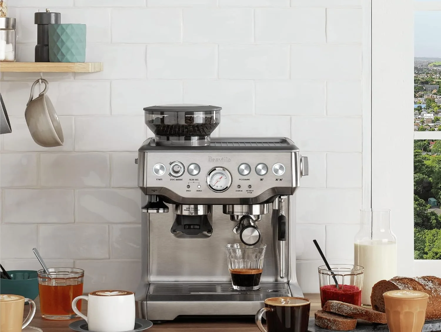 Breville Barista Express on a kitchen counter, pulling an espresso shot beside a freshly poured cappuccino